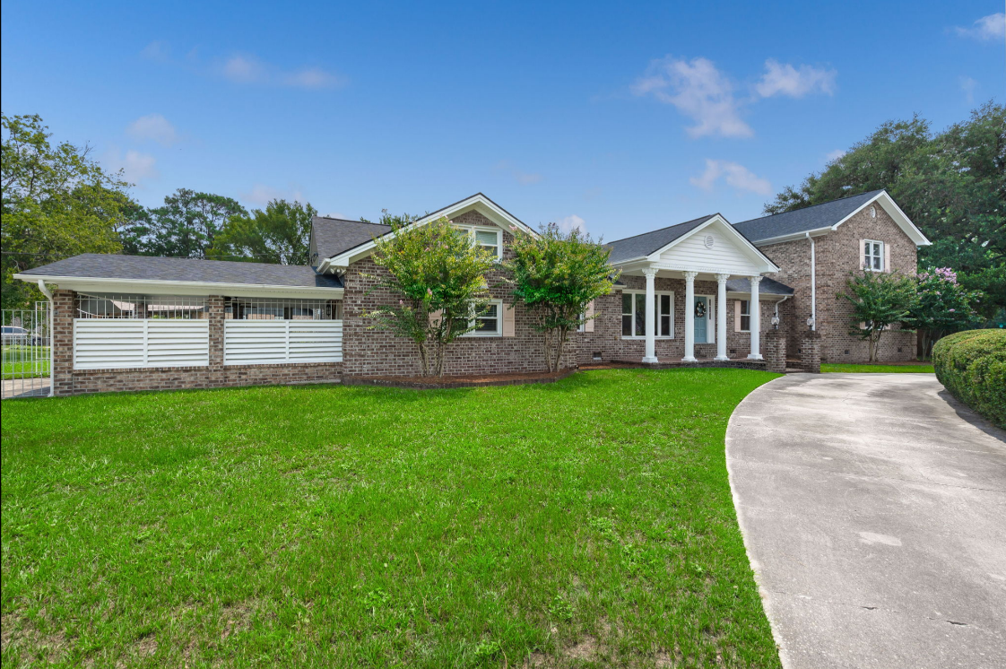 Brick Charleston rental home with white columns and a manicured lawn